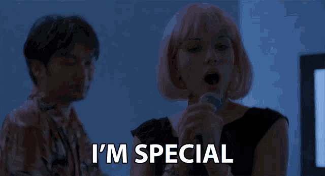 a woman with pink hair is singing into a microphone and the words i 'm special are below her