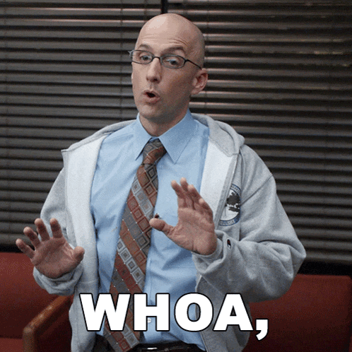 a man wearing glasses and a tie is sitting in a chair and says whoa