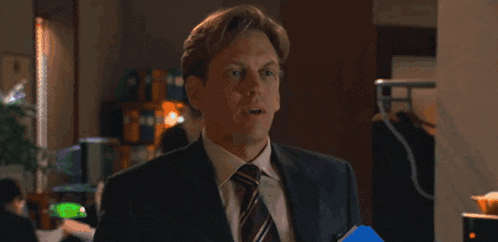 a man in a suit and tie is standing in an office