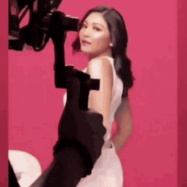 a woman in a white dress is being filmed by a cameraman .