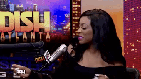 a woman is talking into a microphone in front of a sign that says dish