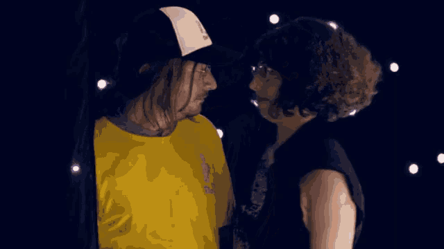 a man wearing a yellow shirt that says ' i love you ' on it looks at a woman