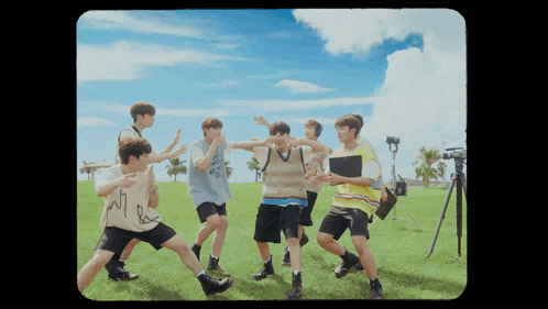 a group of young men are dancing in a field with one wearing a shirt that says mr.