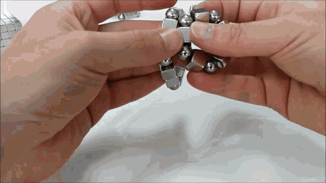 a close up of a person 's hands holding a metal bracelet