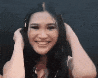 a woman with long black hair is smiling while holding her hair in her hands .