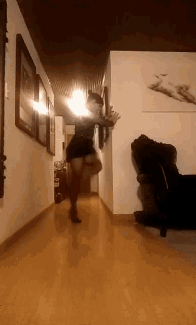 a woman is dancing in a hallway in front of a painting