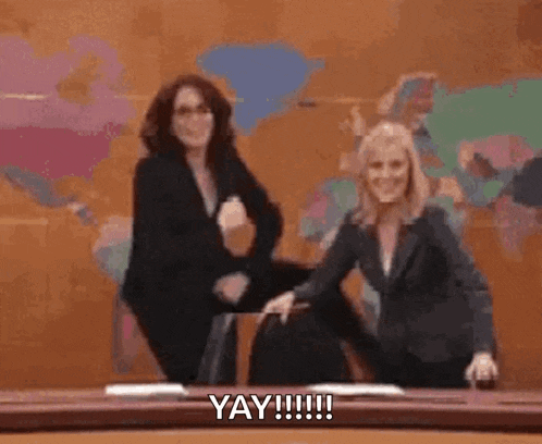 two women are dancing in front of a map of the world and a sign that says yay !!!