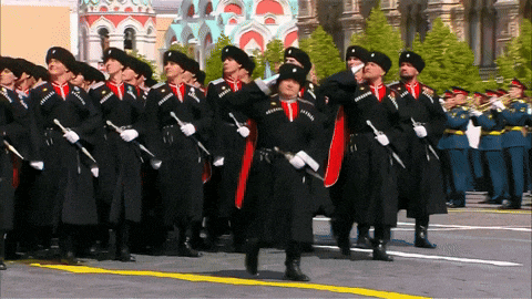 a group of soldiers marching in a parade with a band playing in the background
