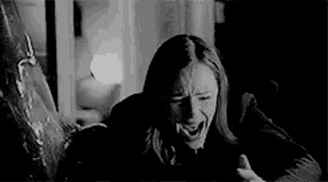 a woman is screaming in a black and white photo while holding a knife .