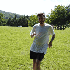 a man in a white shirt and black shorts is running in a field
