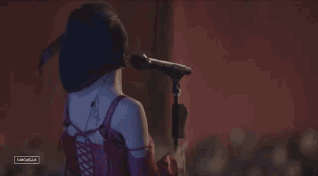 a woman in a red dress singing into a microphone with the word coachella on the bottom right