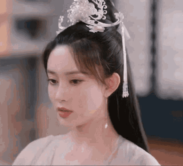 a close up of a woman wearing a crown on her head and earrings .