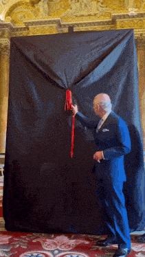 a man in a suit is pulling a red ribbon behind a black curtain
