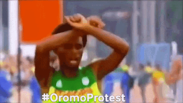a man in a green and yellow shirt is holding his head in protest .