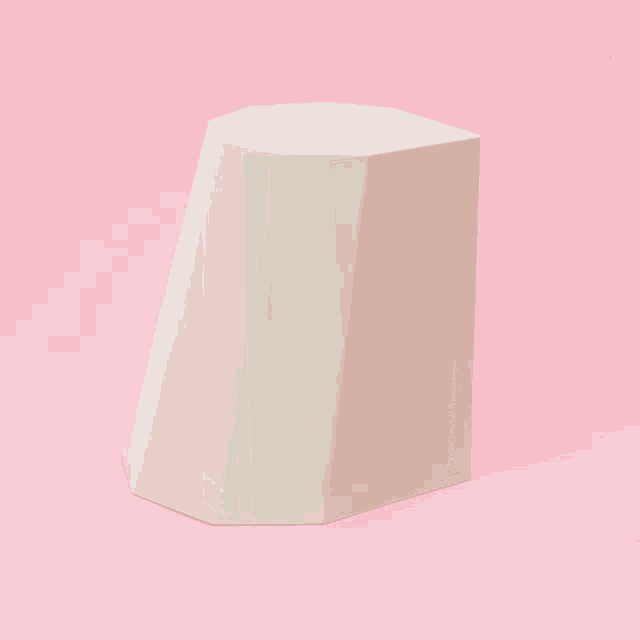 a white hexagon shaped object is on a pink surface