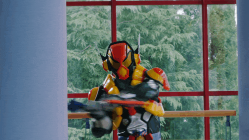 a man in a robot costume is standing in front of a window with trees in the background
