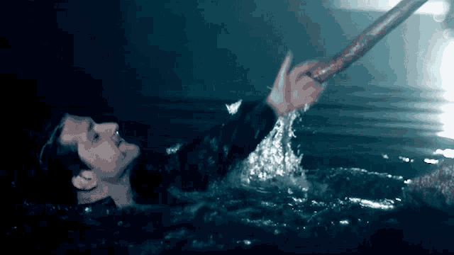 a man is swimming in the water and holding onto a stick