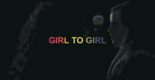 a woman is standing in the dark with the words `` girl to girl '' written in rainbow letters on her face .