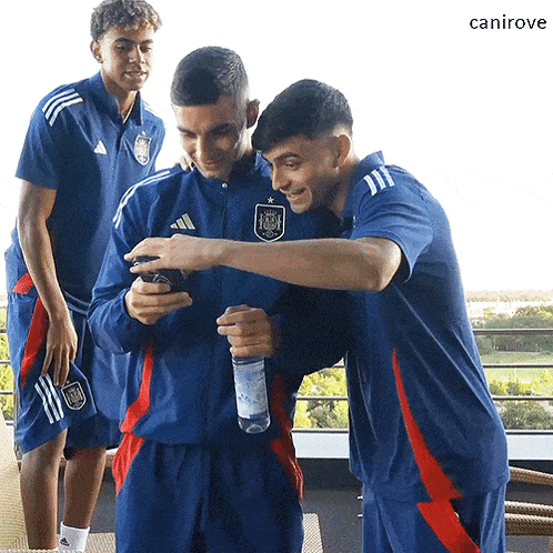 a group of soccer players are posing for a picture and one of them is wearing a blue adidas jacket
