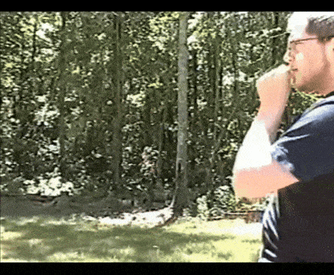 a man with glasses is standing in front of trees