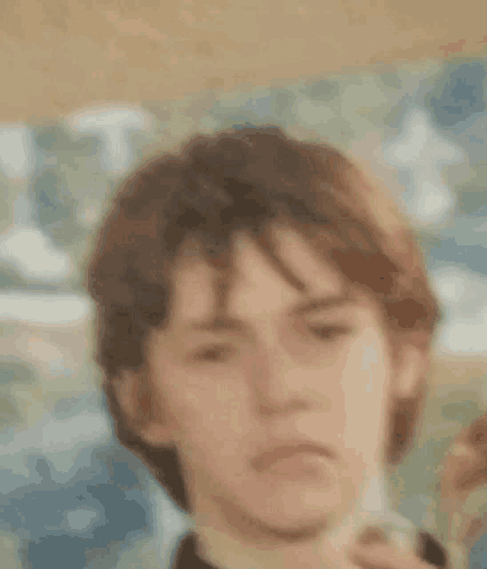 a close up of a young man 's face with a blurred background and a painting in the background .