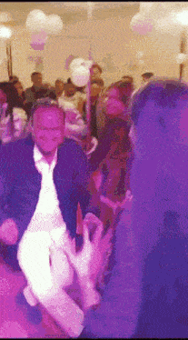 a man in a suit is dancing in a crowded room