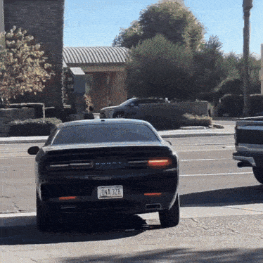 a black dodge challenger has a license plate that says ona 32b