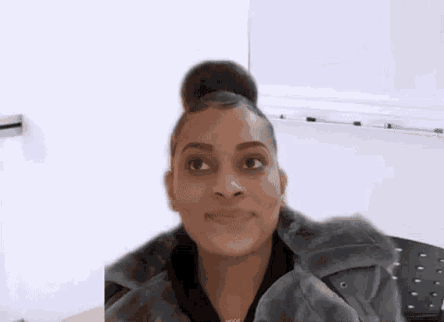 a woman in a fur coat is making a funny face while sitting in front of a white board .