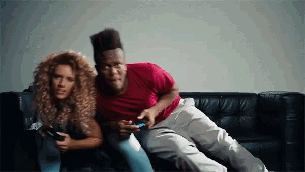 a man and woman are sitting on a couch playing video games