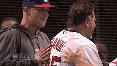 a baseball player wearing a number 5 jersey talks to another man