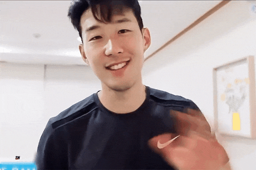 a man wearing a black nike shirt is smiling and waving his hand