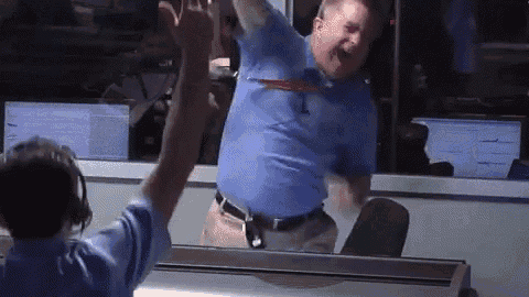 a man in a blue shirt holds his arms in the air