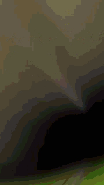 a blurred image of a green field with a dark sky in the background