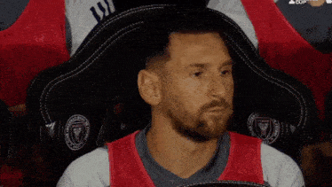 a man with a beard is sitting in a chair with a badge that says ' miami fc ' on it