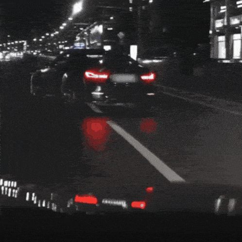 a black and white photo of a car driving down a road at night