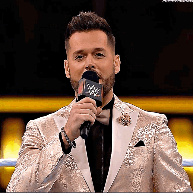a man in a suit is speaking into a microphone with a w on it