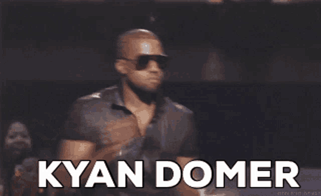 a man wearing sunglasses and a black shirt says kyan domer in white letters