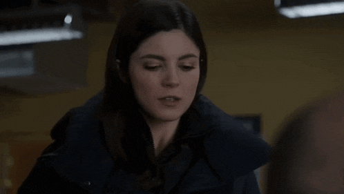 a woman in a blue jacket is looking at a man in a room .