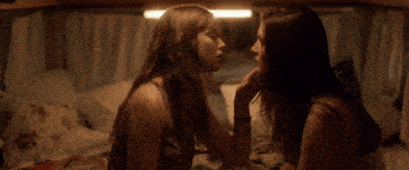 two women kissing in a dark room with a light on