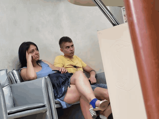 a man in a yellow shirt sits next to a woman in shorts
