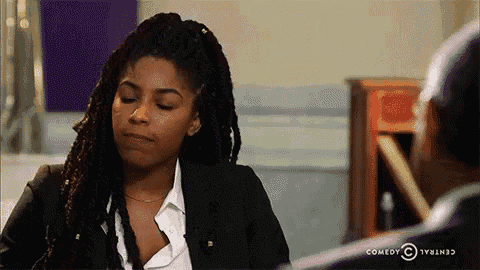 a woman with dreadlocks is sitting at a table with a man and a sign that says comedy central