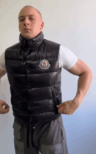 a man wearing a black moncler vest and a white shirt