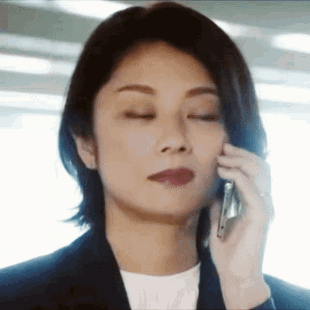a woman in a suit is talking on her cell phone .