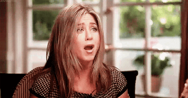 a woman is sitting in a chair with her mouth open and making a surprised face .
