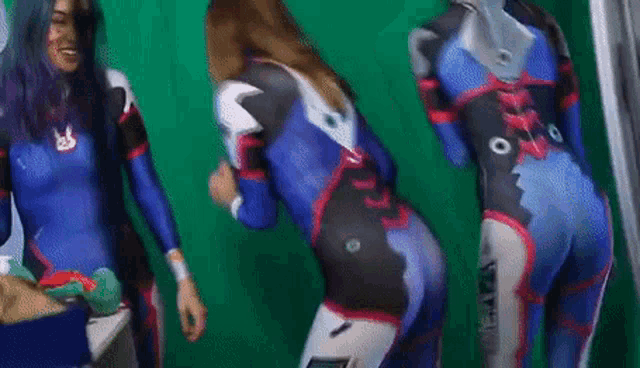 a woman in a blue and black superhero costume is standing in front of a green screen .