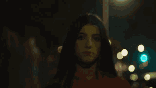 a woman in a red hoodie stands in front of a traffic light