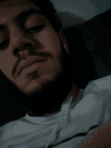 a man with a beard is brushing his teeth with a white toothbrush