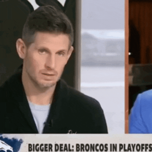 a man is standing in front of a sign that says " bigger deal broncos in playoffs "