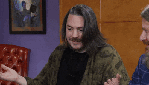 a man with long hair and a beard is sitting in a chair