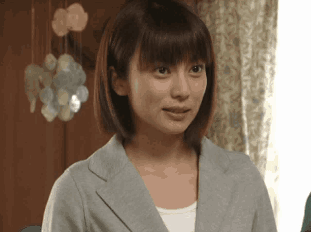 a woman wearing a gray jacket and a white shirt